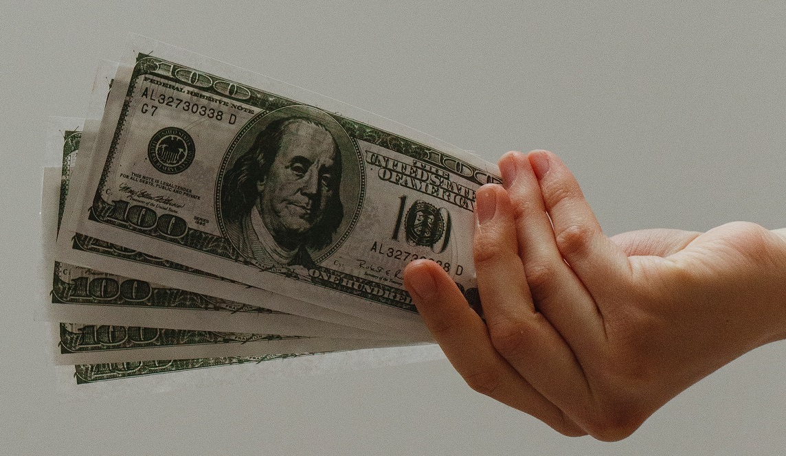 hand holding five $100 bills