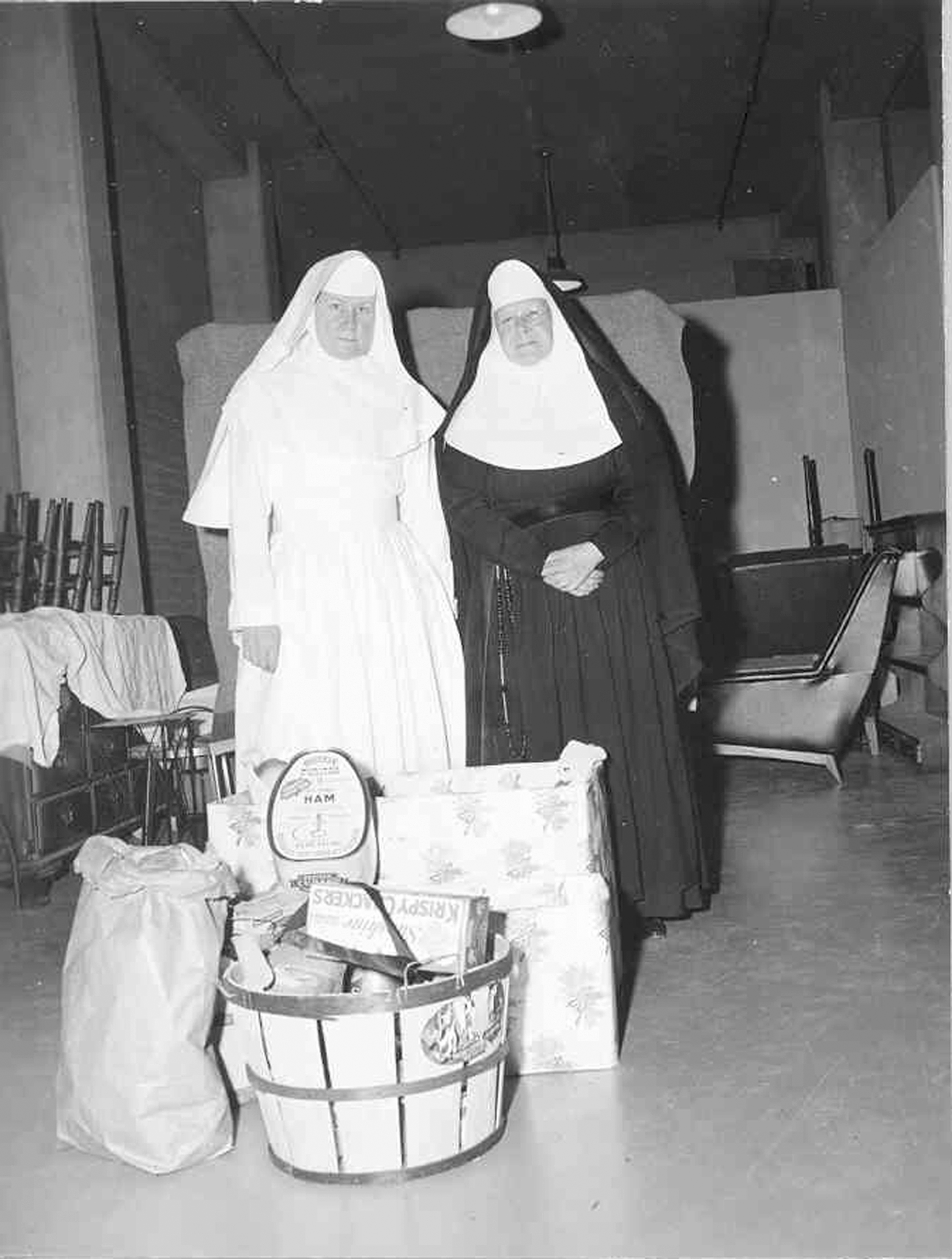 Historic photo of two nuns/nurses with a food donation
